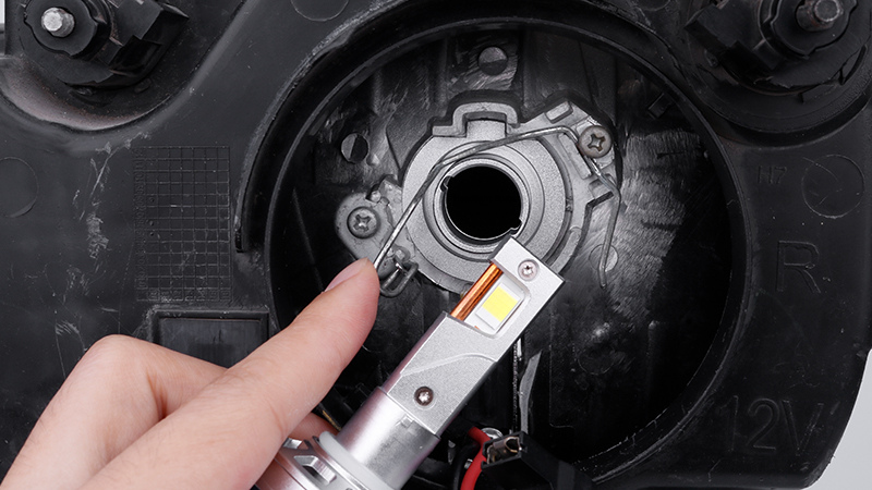 Installing an H1 LED headlight bulb into a car housing.