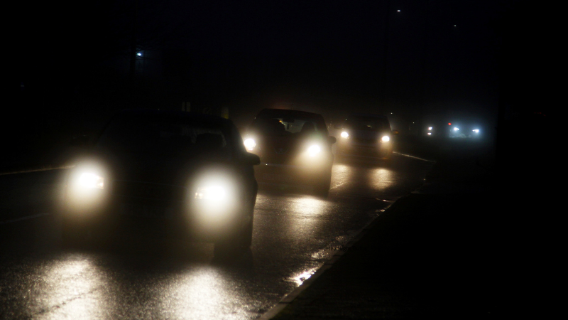 A vehicle traveling on the road with its lights on at night