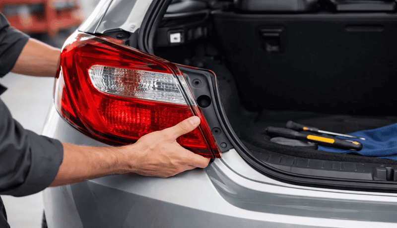 Step-by-step tail light replacement on a car with tools and open trunk