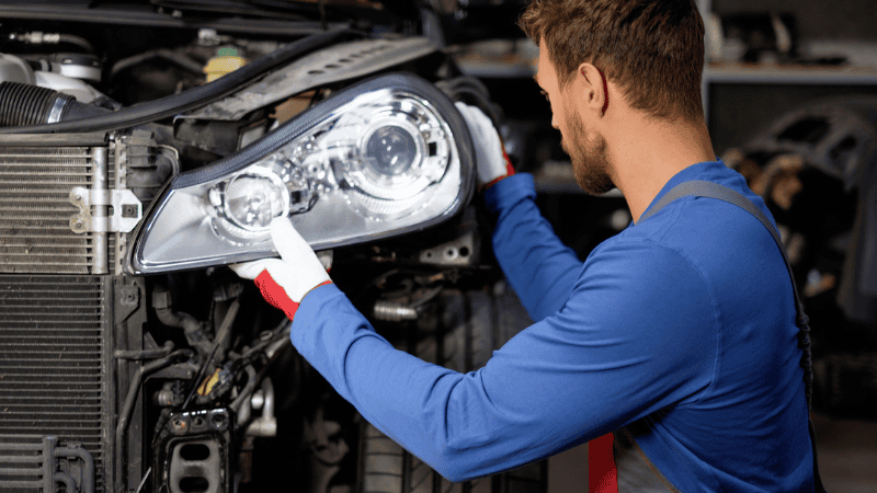 Mechanic with new car headlight in a workshop Maintenance technician 