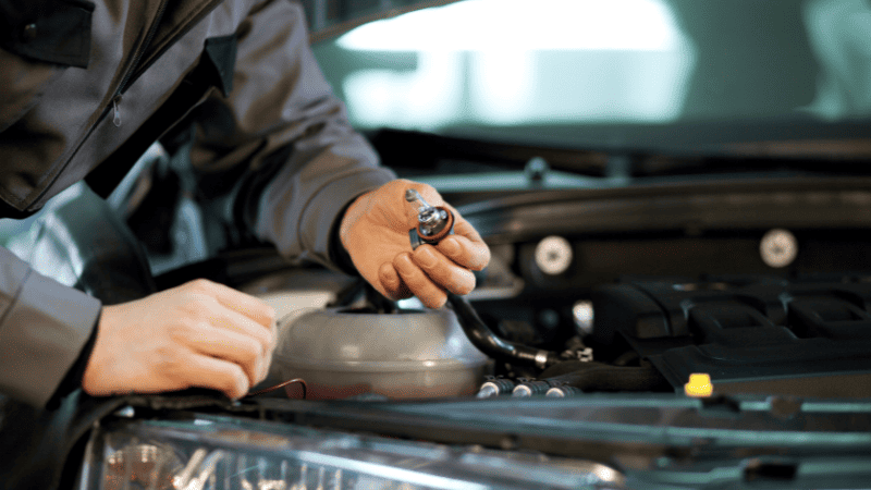 A man is checking the light bulb of the car