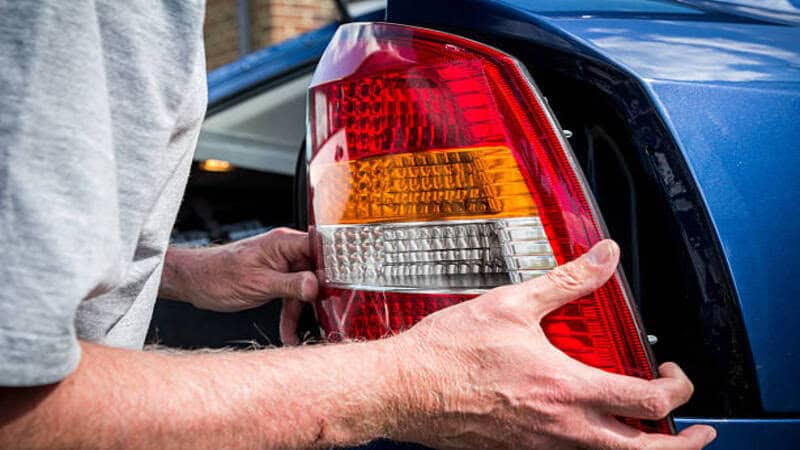 A professional replacing the headlight of a car.