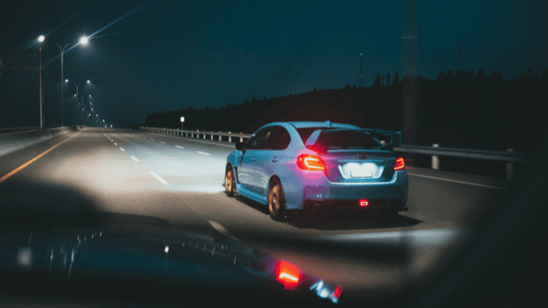 A car traveling down the road with white lights underneath.