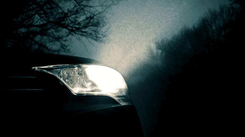 Smart headlights illuminate a path in a dark environment.