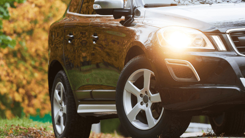 A car is safely parked outdoors. The design of the front headlights and the warm sunlight make the vehicle more elegant.
