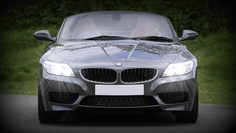 Front view of BMW coupe with headlights on.