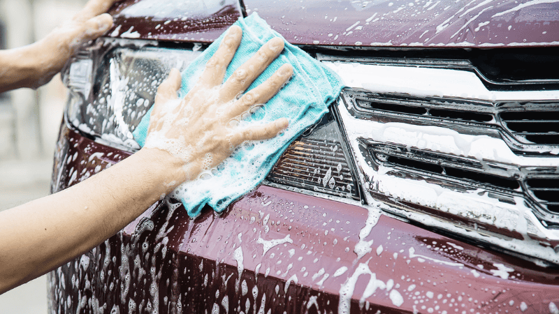 A person cleaning the headlights to maintain it.